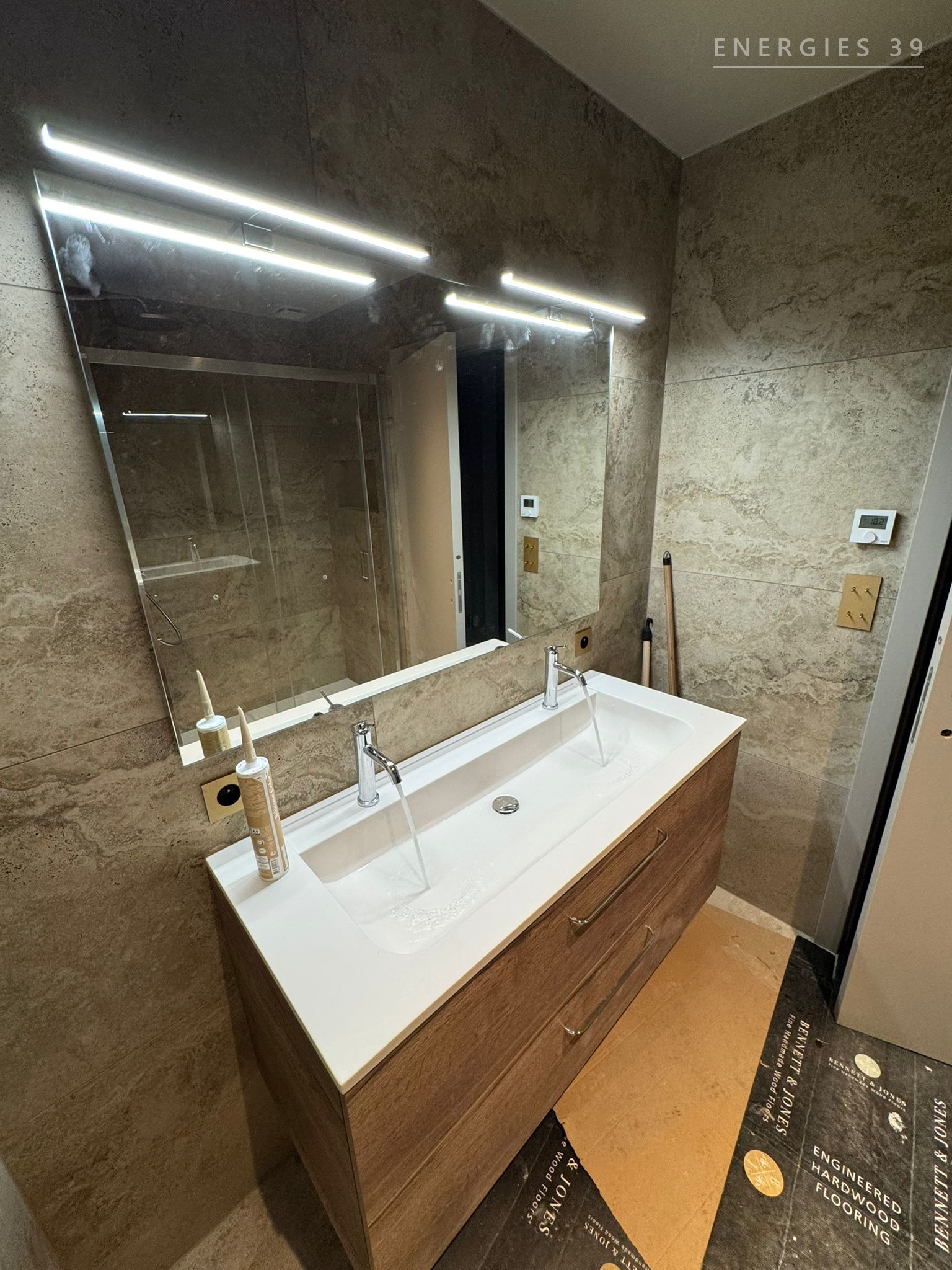 Salle de bain rénovée avec murs en marbre et double vasque suspendue
