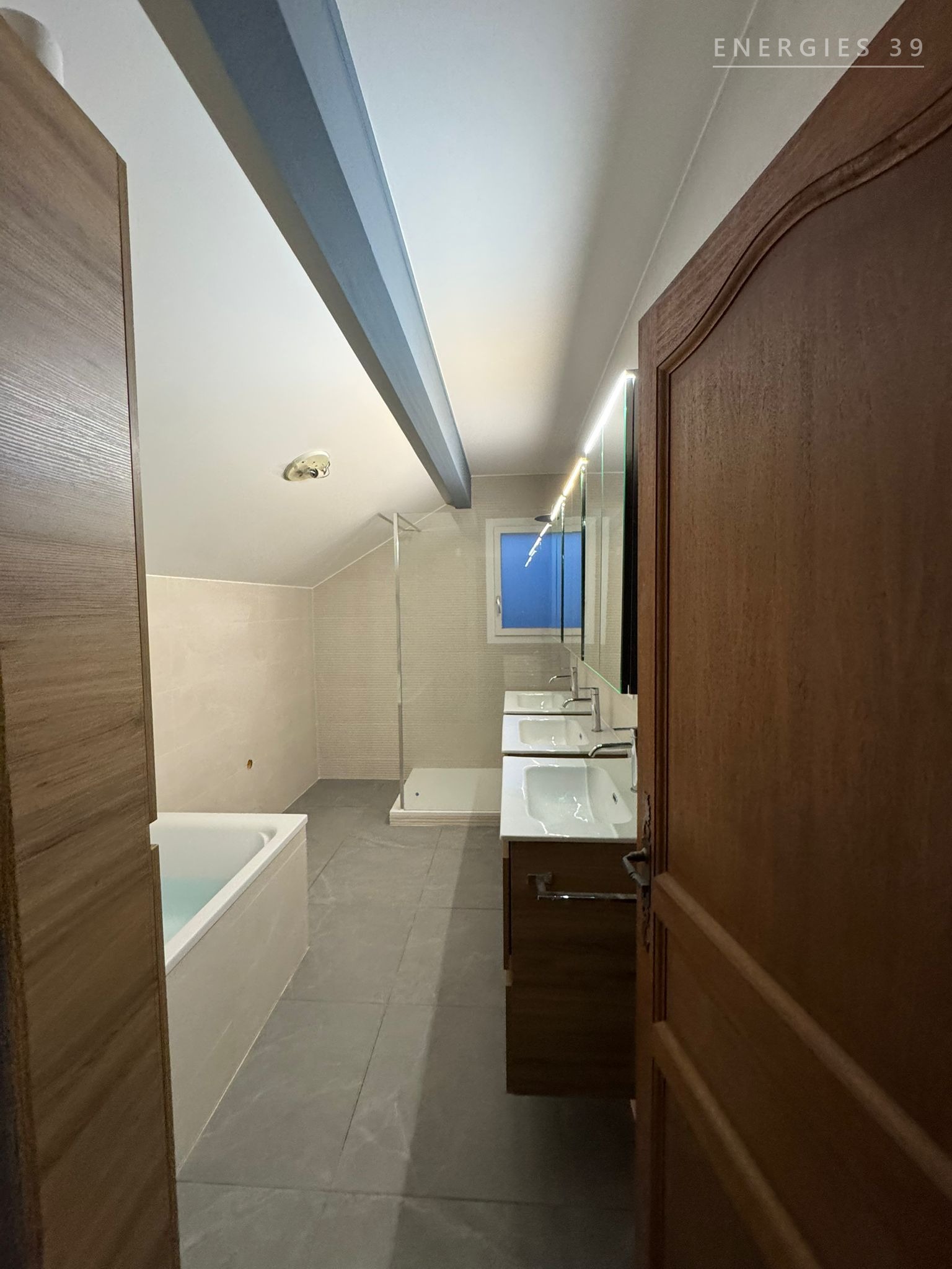 Salle de bain sous combles avec baignoire encastrée et double vasque
